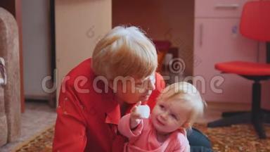小女孩和奶奶在地板上玩耍，奶奶拥抱和亲吻孙女